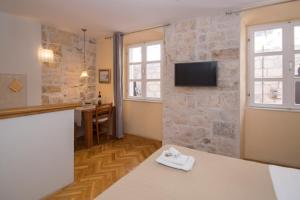 un soggiorno con TV su un muro di pietra di Old Town Apartments a Korčula