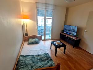 ein kleines Wohnzimmer mit einem TV und einem Tisch in der Unterkunft Versailles Trip Appartement in Buc