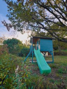 a playground with a green slide and a blue house at Casa Mido Badacsony in Badacsonytomaj