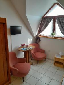 a room with two chairs and a table and a tv at Béke Stúdió Apartman in Fonyód