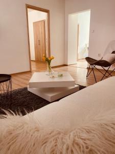 a white room with a table with a vase of flowers at Trio Apartments in Ostrava
