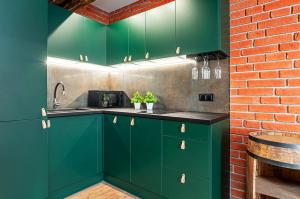 a kitchen with green cabinets and a brick wall at Apartament DWORCOWA 86 in Bydgoszcz