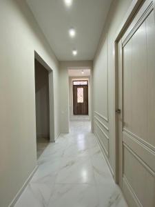 an empty hallway with a door and white tile floor at Lidiani Guest House in Gyumri
