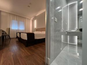 sypialnia z łóżkiem i szklanymi drzwiami prysznicowymi w obiekcie Hotel Alfonso IX w mieście Sarria