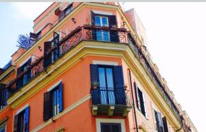 ローマにあるGolden Rooms Piazza di Spagnaのバルコニーと窓が備わる高いオレンジ色の建物です。