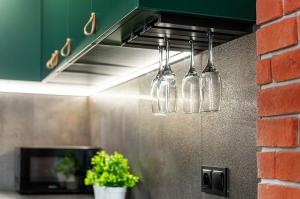 a group of wine glasses hanging from a rack in a kitchen at Apartament DWORCOWA 86 in Bydgoszcz +4 photos