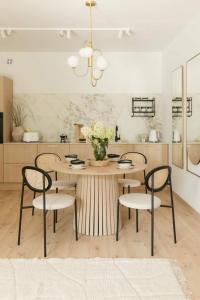 a kitchen with a table with chairs and a vase of flowers at Panorama Apart 23 in Olsztyn