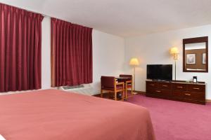 a hotel room with a bed and a flat screen tv at America's Best Value Inn Beardstown in Beardstown