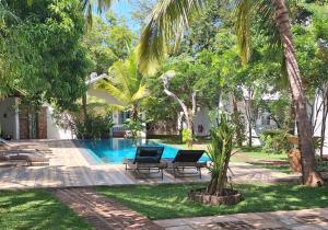 a swimming pool in a yard with two chairs and trees at Kandalama Lodge in Dambulla
