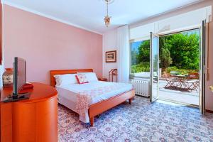a bedroom with a bed and a television and a balcony at Christa Guest House in Massa Lubrense
