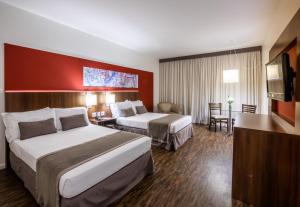 a hotel room with two beds and a television at Hotel Panamby Guarulhos in Guarulhos