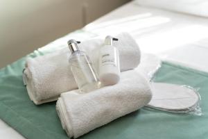 een paar handdoeken en een fles op een bed bij Happinest Private Apartment in Kalymnos