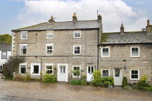 an old brick house with white doors and windows at Penny Pot Cottage in Middleham