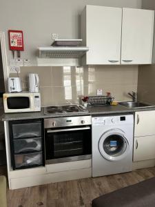 a kitchen with a stove and a washing machine at 1 Bed apartment with a balcony in London