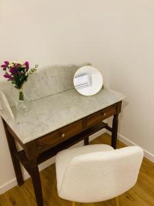 a desk with a vase of flowers and a mirror at Charming home near Paris in Le Perreux-Sur-Marne