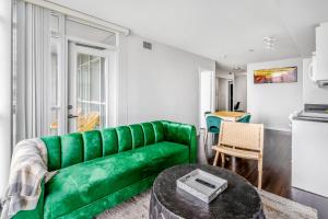 a living room with a green couch and a table at Family oriented Downtown Toronto 2BDRM Condo with Parking & office space in Toronto