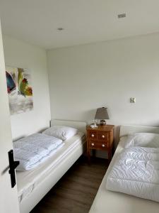 een slaapkamer met 2 bedden en een nachtkastje met een lamp bij Bungalow kleine Deichperle, Strand und Deich in unmittelbarer Nähe! in Lemmer