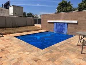 einen blauen Pool auf einer Terrasse mit einem Tisch in der Unterkunft Apartamento no Jardim Goiás em Goiânia in Goiânia