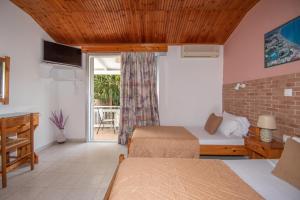 a room with two beds and a door to a patio at Theodora Studios Best Location In Laganas Next To The Party Area in Laganas