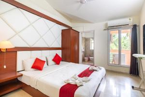 um quarto com uma grande cama branca com almofadas vermelhas em Johnnie Holiday Homes em Arpora
