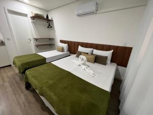 two beds in a room with green and white at SeuLar o conforto de um Lar em Qualquer Lugar in São Paulo