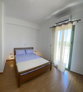 a bedroom with a bed and a large window at La nymphe Aegina in Áyioi Asómatoi