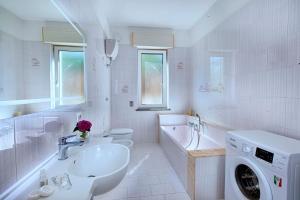 a white bathroom with a sink and a washing machine at Christa Guest House in Massa Lubrense