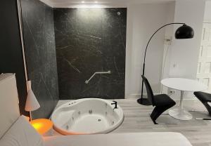 baño con bañera y pared negra en H. Pelayo Autocheck-In Suites con Jacuzzi, en Noja