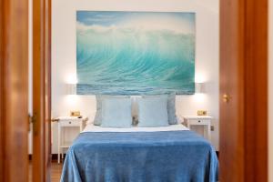 a bedroom with a bed with a painting on the wall at Palm Beach House in Corralejo