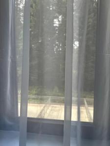 una finestra con tende bianche e vista su un campo di Апартхотел Флора 213Б a Borovets