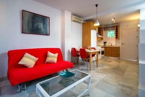 a living room with a red couch and a table at DescubreHome Sol Town Center Private Terrace in Seville