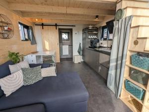 uma sala de estar com um sofá azul e uma cozinha em Klavertje 4 em Middelaar