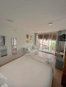 a white room with a large bed and a couch at Estadía en hermoso hotel en la isla de punta arena cartagena in Playa Punta Arena