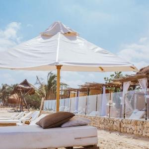 a bed under a white umbrella on the beach at Estadía en hermoso hotel en la isla de punta arena cartagena in Playa Punta Arena