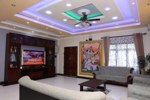 een woonkamer met een plafondventilator en een televisie bij Hajiz Palace in Jaffna