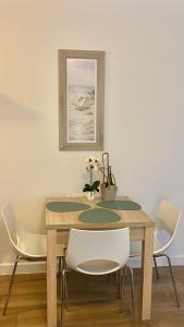 uma mesa de jantar com cadeiras brancas e uma fotografia em NATURAvistaMARE IV Świnoujście Aquamarina C20 em Świnoujście