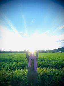 a person standing in a field with the sun in the sky at Khalish Homestay Pokok Sena in Pokok Sena