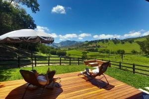 two chairs and an umbrella on a wooden deck at Chalés do Mato Dentro in Paraisópolis