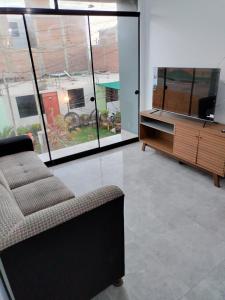 sala de estar con sofá y TV de pantalla plana en Airbnb Paracas Inn, en Pisco