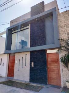 a house with a large window and wooden doors at Airbnb Paracas Inn in Pisco