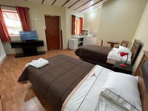 a hotel room with two beds and a television at Anka Wasi Lodging in Cusco