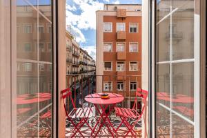 une table et des chaises rouges sur le balcon d'un bâtiment dans l'établissement BNBHolder Charming & Stylish CHUECA, à Madrid