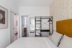 - une chambre avec un lit blanc et un mur en briques dans l'établissement BNBHolder Charming & Stylish CHUECA, à Madrid