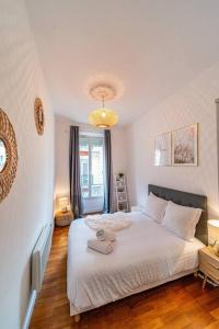 - une chambre avec un grand lit blanc et un lustre dans l'établissement Coeur centre ville Grenoble - charme de l'ancien, à Grenoble