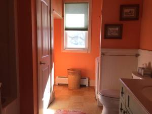 an orange bathroom with a toilet and a window at Waterfront Home on Bantam Lake with Private Beach in Morris