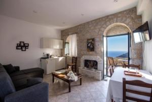 a living room with a couch and a kitchen with a fireplace at Olga's House in Neo Itilo