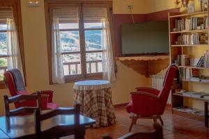 a room with chairs and a table and a tv at Pension Las Cuevas de Cañart in Las Cuevas de Cañart