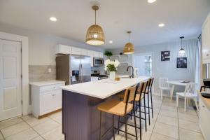 a kitchen with white cabinets and a island with bar stools at Cozy Virginia Home in Lynchburg Historic District! in Lynchburg