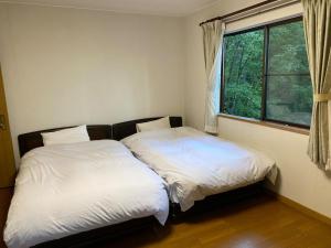 2 camas sentadas junto a una ventana en un dormitorio en [Luxury villa with BBQ facilities overlooking Moun - Vacation STAY 14273, en Oishi