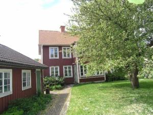 una casa roja con un árbol delante en Central villa med extra allt. Pool, Bastu, Utekök en Kalmar